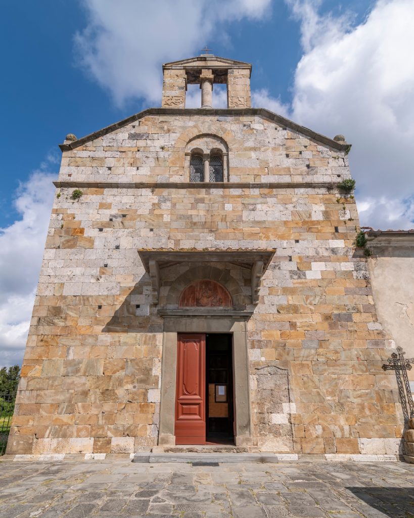 Facciata romanica della Chiesa di San Giorgio a Bibbiano, nel comune di Cascina, con muratura in pietra, portale d’ingresso e campanile a vela.